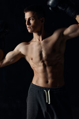 guy with a pumped-up torso gesturing with his hands on a black background boxing gloves 