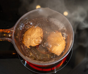 Two eggs boiling in a glass pan on a ceramic hob