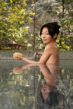 Portrait beautiful nude young woman with loofah in pool at Onsen
