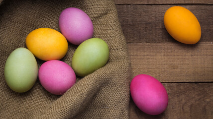 bright Easter eggs on the rough texture of burlap on the background of a wooden table