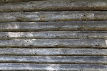 Old weathered grey wooden wall of old log cabin house, horizontal texture for background