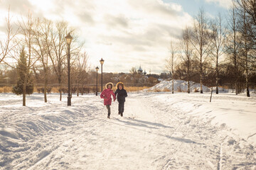 two children, a brother and a sister, run and play on a frosty sunny day, selective focus