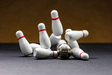Bowling. Bowling ball knocking down pins on a black background with yellow backlighting. Copy space. Space for text
