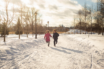 two children, a brother and a sister, run and play on a frosty sunny day, selective focus