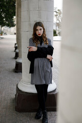 Obraz premium Full length image of the beautiful red-haired girl with make-up, looking at camera, standing near columns.