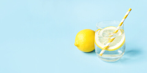 Glass of water with lemon on a blue background. Summer refreshing drink.