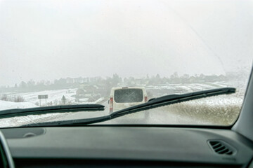 Car wipers wiping the windshield. Winter highway during snowfall	