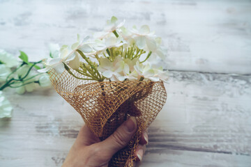 small bouquet decorated with golden netting in womans hand