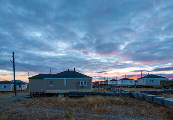 Fototapeta premium Arctic settlement in the tundra. View of residential buildings at dawn. The village of Amguema in Chukotka in the Far North of Russia. Rural autumn landscape. Amguema, Chukotka, Polar Siberia, Russia.