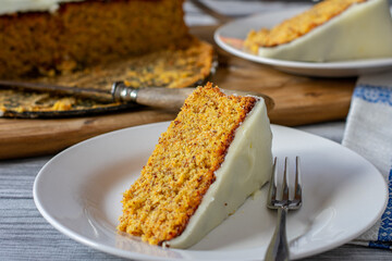 Piece of carrot cake on a plate with fork on kitchen table background. Front view
