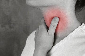 Woman touches the throat with pain, area of red color on black and white
