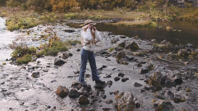 Young Woman Photographing With Camera From Rocks In River