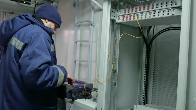 Network engineer in server room with optical patchcord.