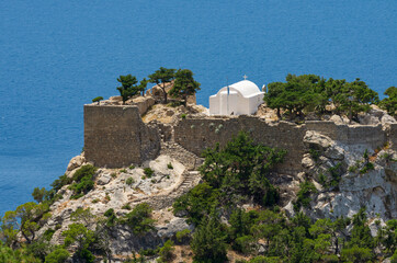 Monolithos medieval fortress and church on a mountain cliff against the backdrop of the magnificent Aegean Sea (Rhodes, Greece)