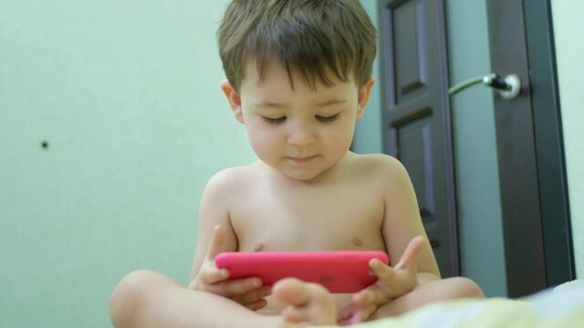 Adorable little kid son using smartphone watching funny videos