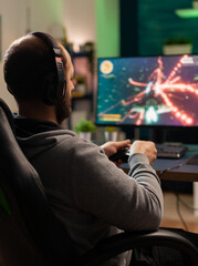 Cyber man with headset playing game in competition holding wireless controller in professional...