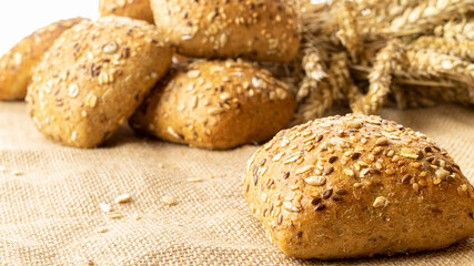 Home baked bread. Rye bakery with crusty loaves and crumbs. Fresh rustic traditional bread with wheat grain ear or spike plant on natural cotton background. Design element for bakery product label.