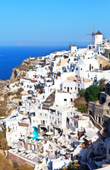 Fototapeta na wymiar The picturesque village of Oia with white Cycladic houses and a windmill on a hill, Santorini, Greece