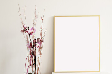 empty vertical golden picture frame with pink orchid flower on the table, mockup for arts, pictures, posters