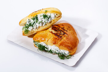 Blush bun with ricotta cheese and dill on in a disposable paper plate on a white background. Delicious hearty snack, breakfast, lunch.