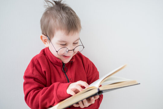 Cute Cheerful Little boy reading a book in glasses. Smart preschooler. Back to school concept	