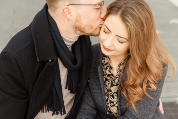 Young couple is walking along the sea. Couple in love look at each other with love and smile. 