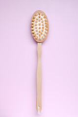 Vertical image.Wooden brush for dry massage on the bright pink surface