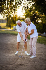 Man teaches a woman to play golf.