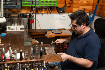 goldsmith jeweler heats a piece of silver with a gas torch to make a ring.