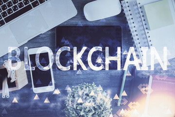 Double exposure of blockchain theme hologram over table with phone. Top view. Crypto technology...