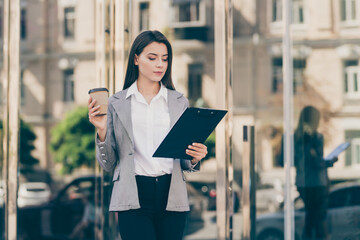 Photo of young beautiful stunning serious businesswoman in blazer reading document in organizer...