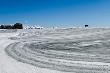 Fototapeta na wymiar 3月の美瑛町 融雪剤がまかれた丘と小屋のある風景 