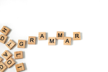 Top view of word grammar made of square wooden tiles with the English alphabet scattered on a white background with space for text. The concept of thinking development, grammar.