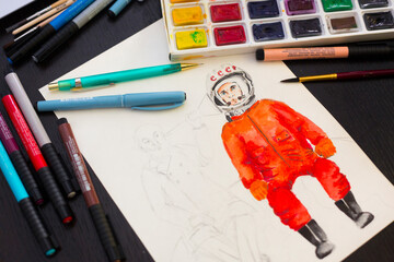 Unfinished watercolor picture of the first Russian cosmonaut Gagarin and scientist Tsiolkovsky, palette, brushes and markers