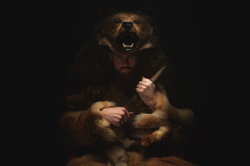 A male shaman werewolf in the skin of a bear sits in a dark room and reflects. Ancient warrior with...