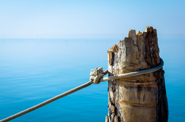 una corda tesa annodata a un palo di legno nella laguna di Venezia a Pellestrina - obrazy, fototapety, plakaty