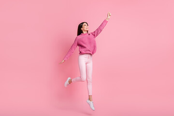 Full size photo of brunette girl jump look empty space wear pink sweater pants sneakers isolated on...