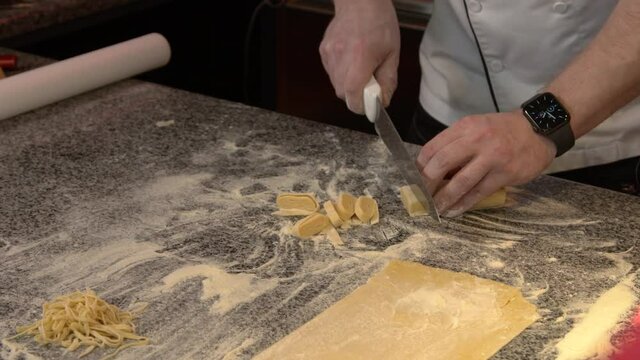 man's hands cut the dough for Manicotti Bucatini Farfalle Gemelli Tortellini