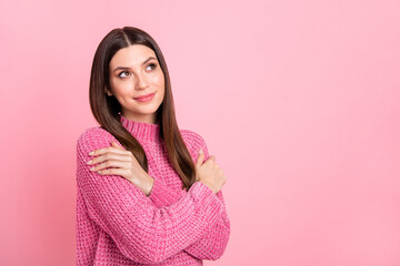 Fototapeta premium Portrait of brunette optimistic girl hug herself look empty space wear pink sweater isolated on crimson color background