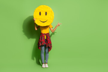 Photo of charming funny dark skin lady dressed t-shirt hiding smiley face pointing empty space...