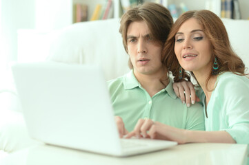 Young couple hugging and looking at laptop at home