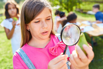 Girl looks at a pear under a magnifying glass