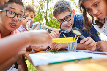 Group of children with magnifying glass learns about plants