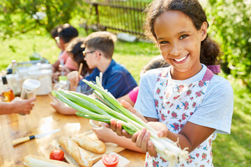 Happy girl in cooking class preparing salad