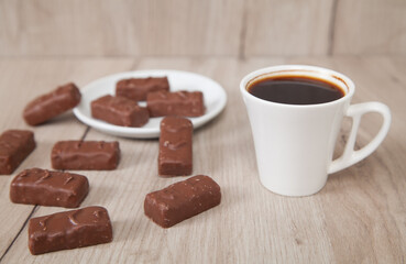 Delicious chocolate candies with coffee on a wooden background.