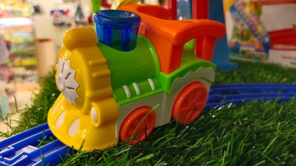 Fototapeta na wymiar A staged detail shot of grass, train tracks, and toy train with blur background.