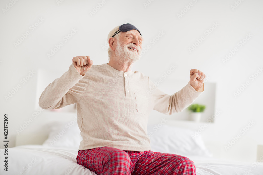 Sticker Photo of aged sleepy man happy positive smile sit on bed home stretching wake up wear pajamas eye mask