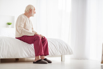 Photo of lonely frustrated age pensioner sleepwear sitting bed looking window inside indoors home...