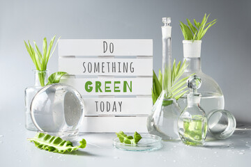 Green laboratory. Text Do Something Green Today on white pallet. Exotic green leaves in water....
