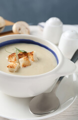 Delicious cream soup with croutons in bowl on table, closeup